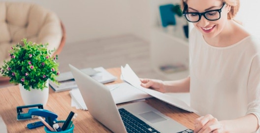 Mujer con computadora y papeles en mano