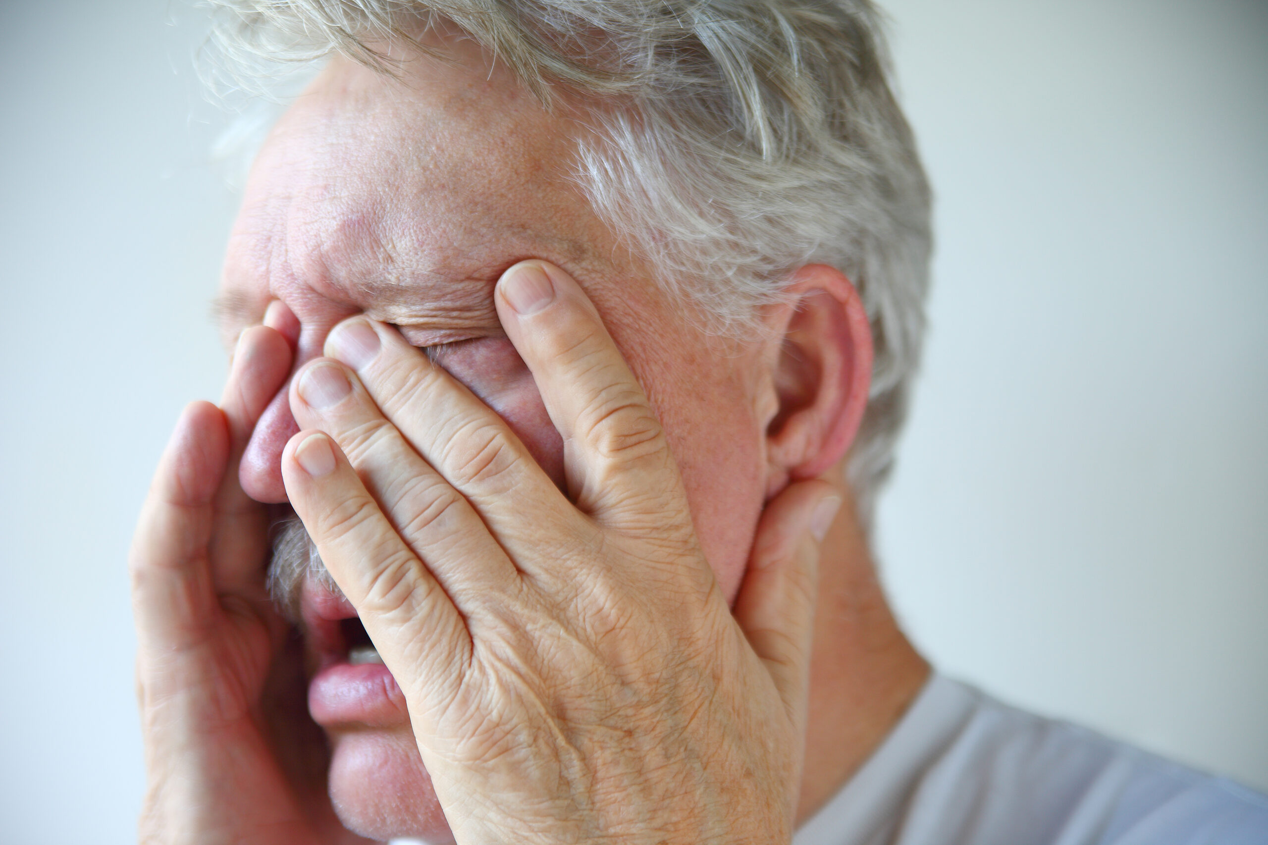 A senior man experiencing stuffy nose, clogged sinuses and headache of a bad flu or cold
