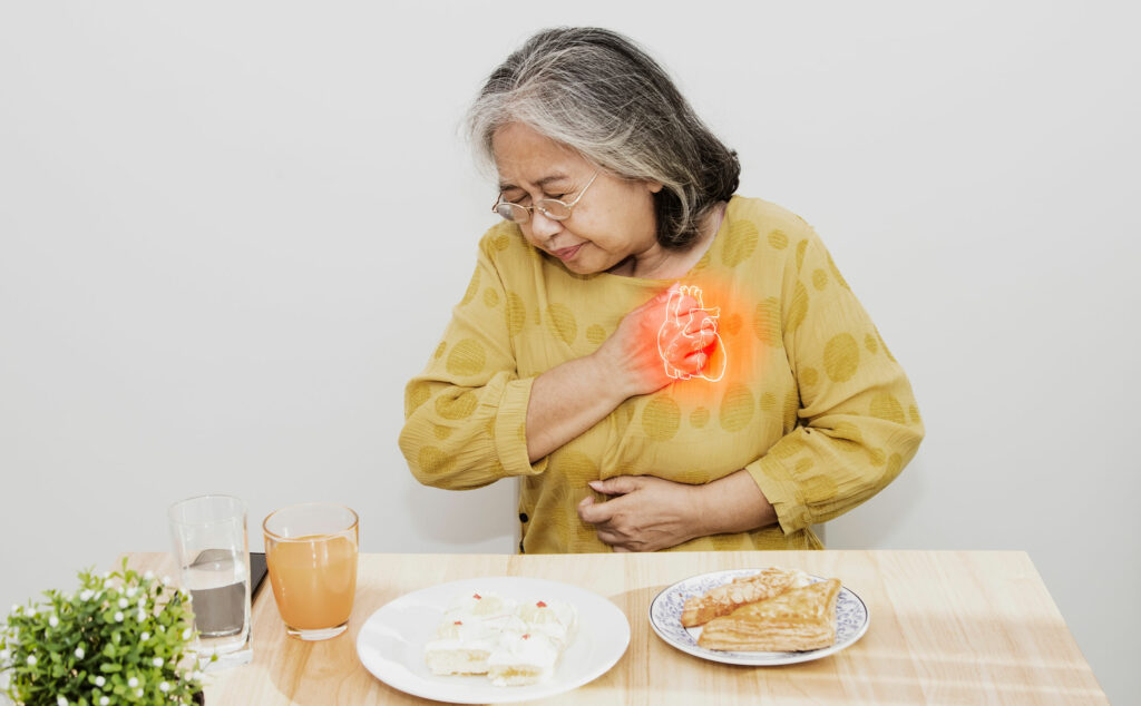 Mujer mayor apretándose el pecho y abdomen debido a que está sintiendo los síntomas de un pre infarto silencioso.