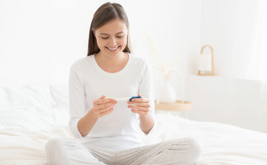 Mujer contenta viendo el resultado de una prueba de embarazo