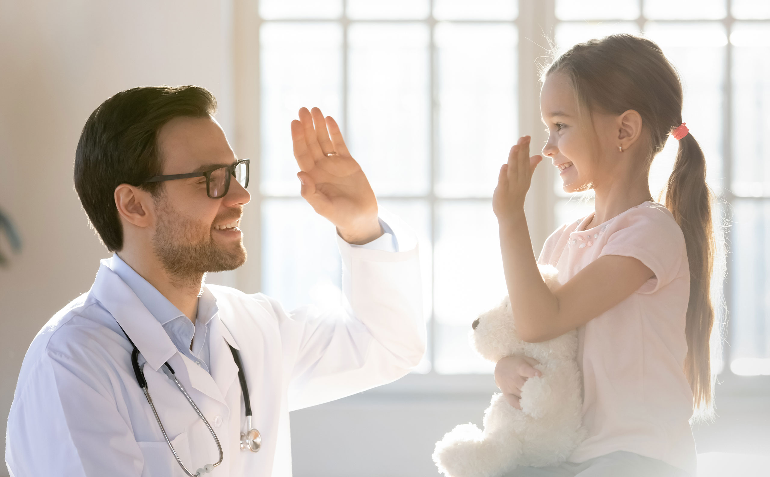 Médico pediatra chocando las manos con su paciente