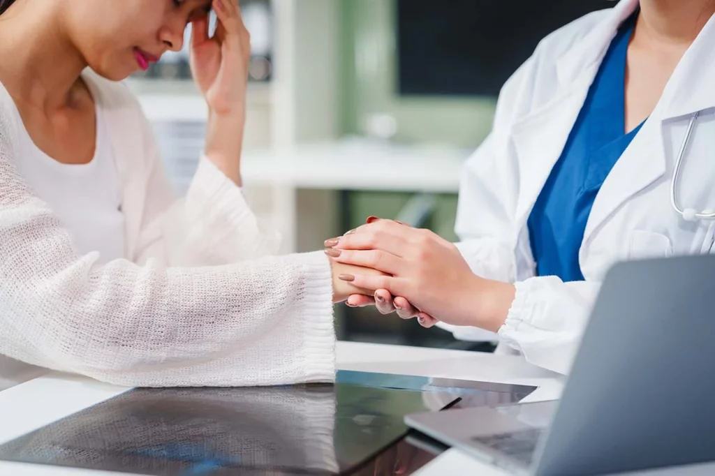 Doctora toma la mano de su paciente mientras le explica los diferentes tipos de esquizofrenia.