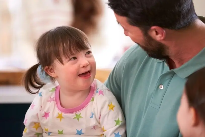  Niña con síndrome de Down sonriéndole a su padre.
