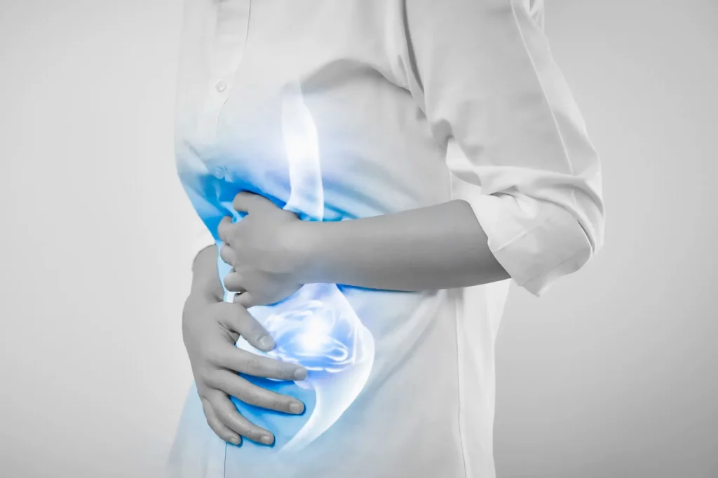 Mujer sufriendo de un dolor por gastritis y agarrándose el estómago con sus manos.