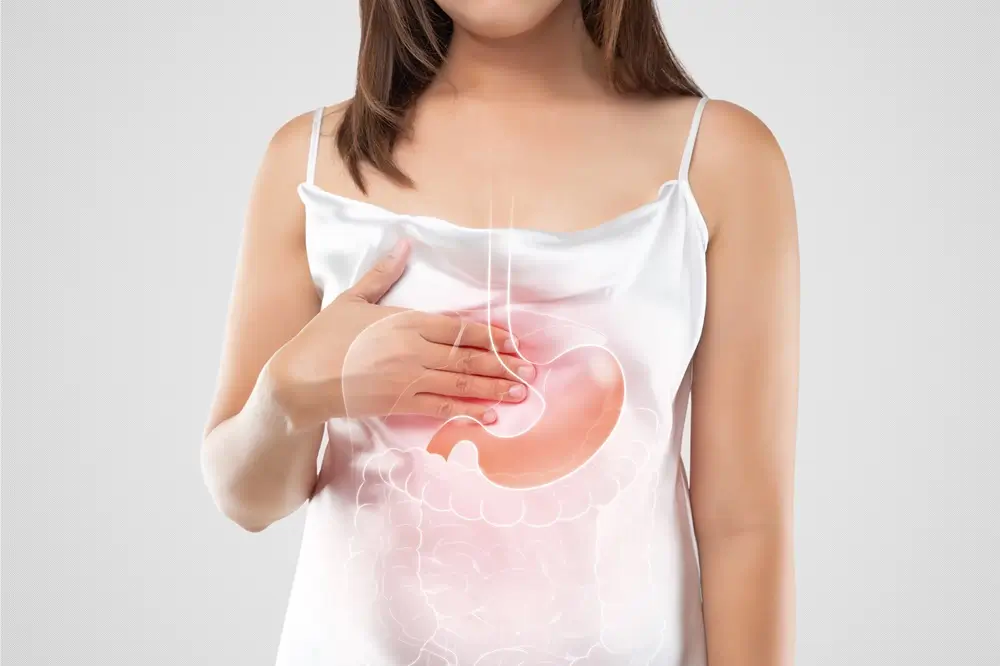 Mujer se presiona el estómago a consecuencia de reflujo gastroesofágico.
