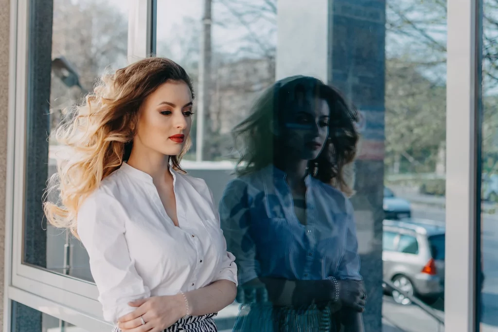 Mujer que presenta trastorno límite de la personalidad caminando por la calle y con su reflejo en un cristal