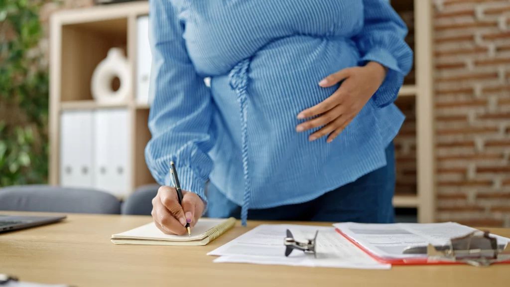 Mujer embarazada trabajando escribiendo y tocando su vientre