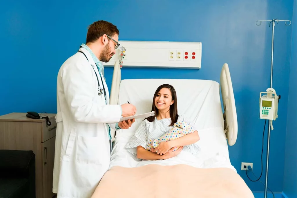 Madre con bebé en brazos recibiendo atención de neonatología posterior al parto.
