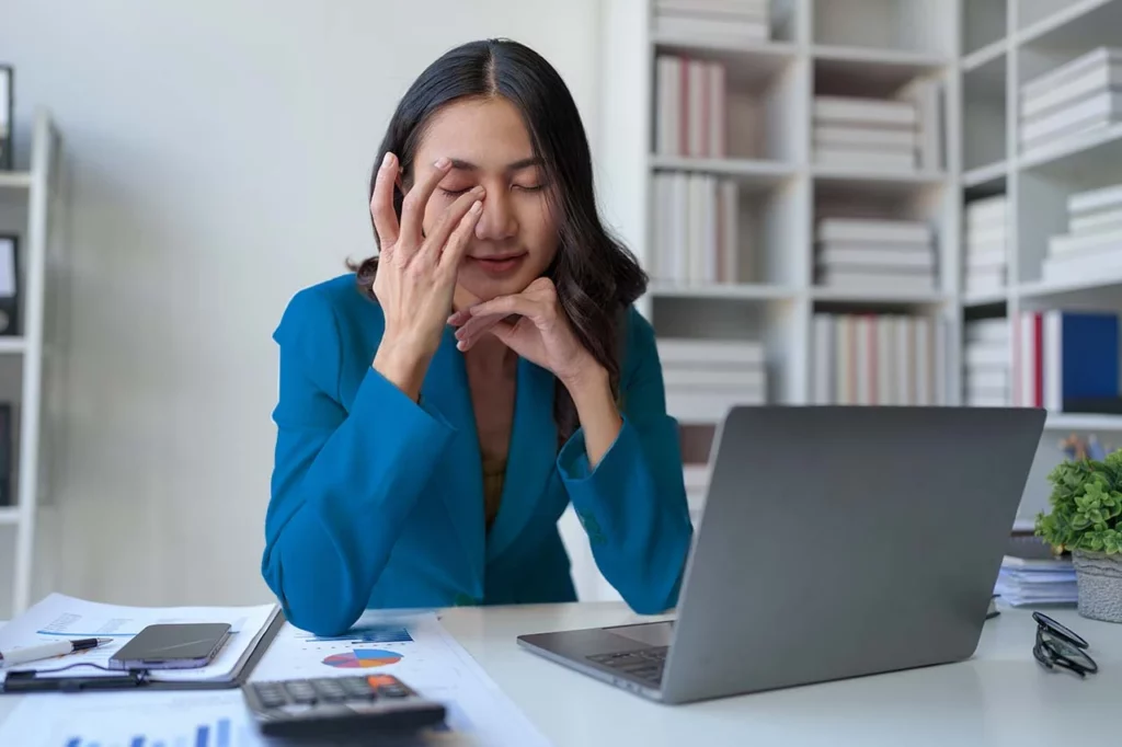 Mujer trabajando con cansancio ocular por trabajar con computadora portátil