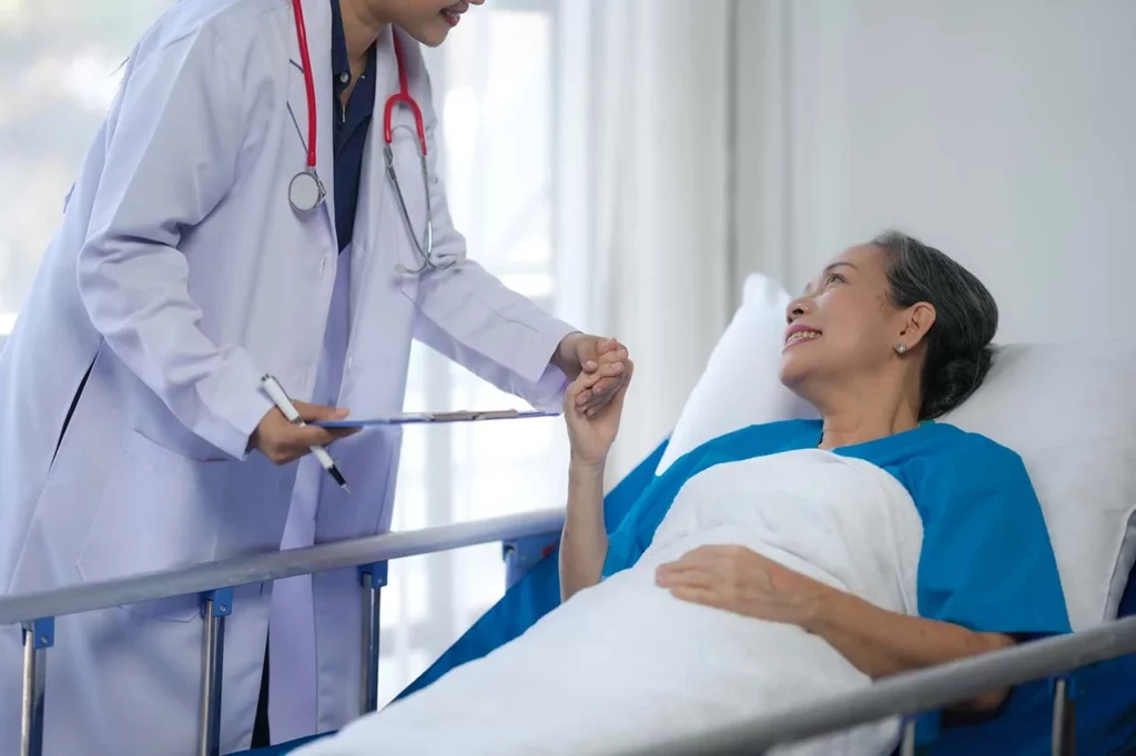 Mujer en camilla sonriéndole al doctor que le proporciona sus cuidados paliativos.
