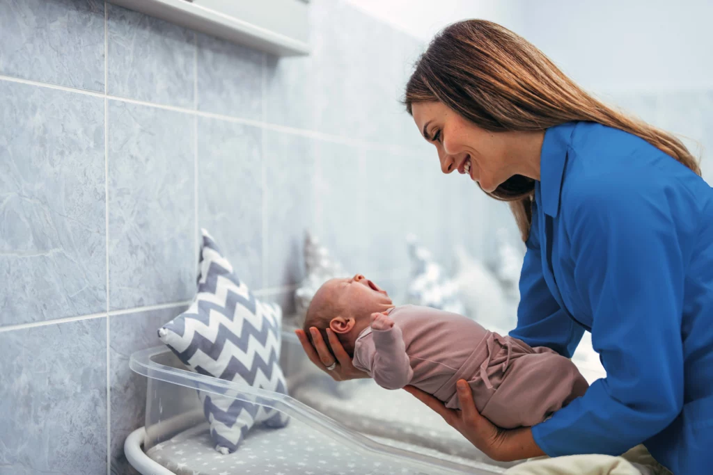 Mujer cargando a su bebé recién nacido, después de que le hicieran el tamiz neonatal.
