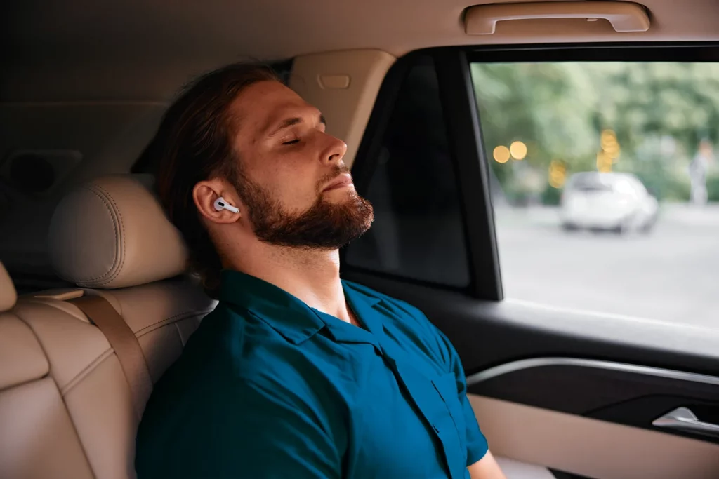 Hombre en su coche escuchando música que es su herramienta de cómo controlar la ansiedad. 
