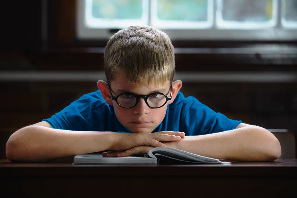 Niño recargado sobre un libro, ya que presenta lo que es dislexia y se le dificulta la lectura.