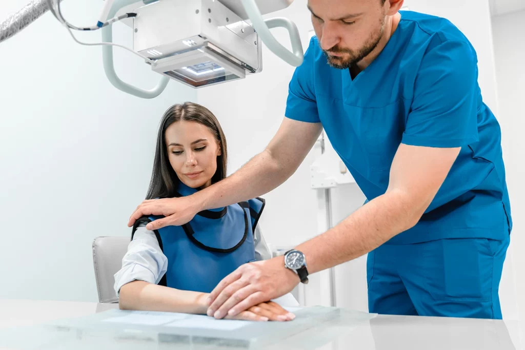 Especialista en radiología musculoesquelética acomodando la mano de una paciente para sacarle una radiografía.
