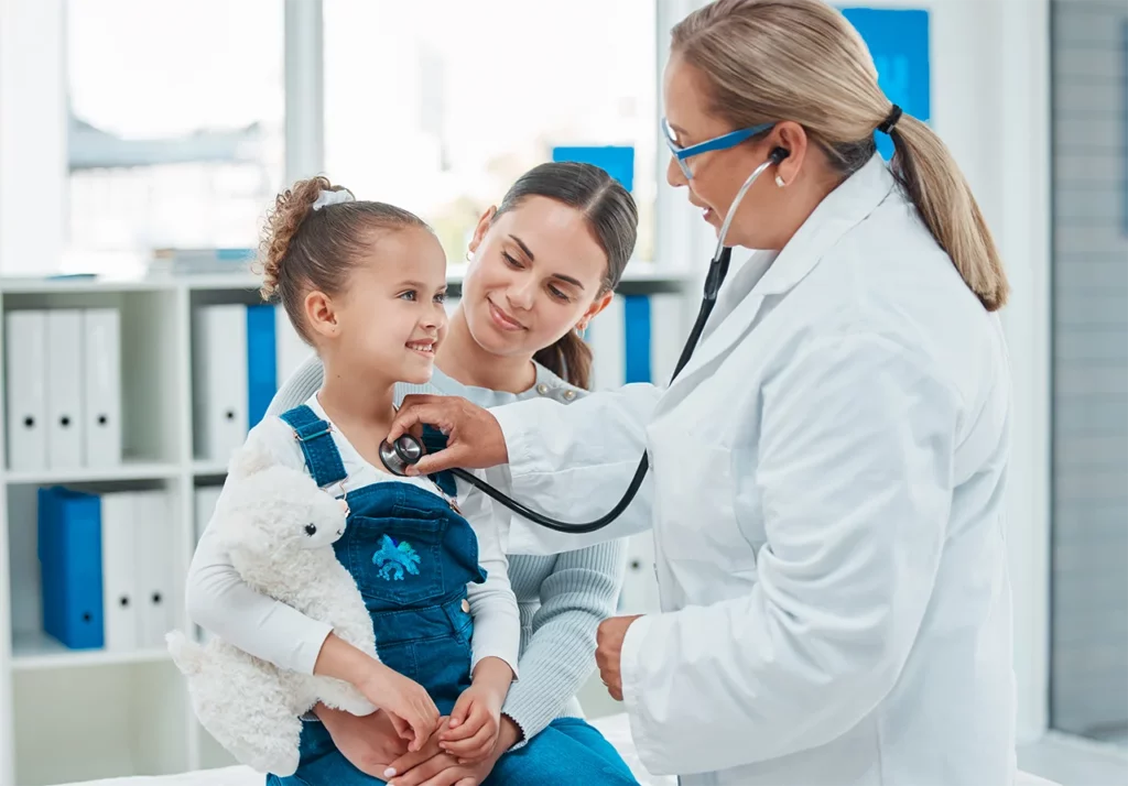 Paciente de cardiología intervencionista pediátrica con su madre; la doctora le está haciendo un chequeo de control.
