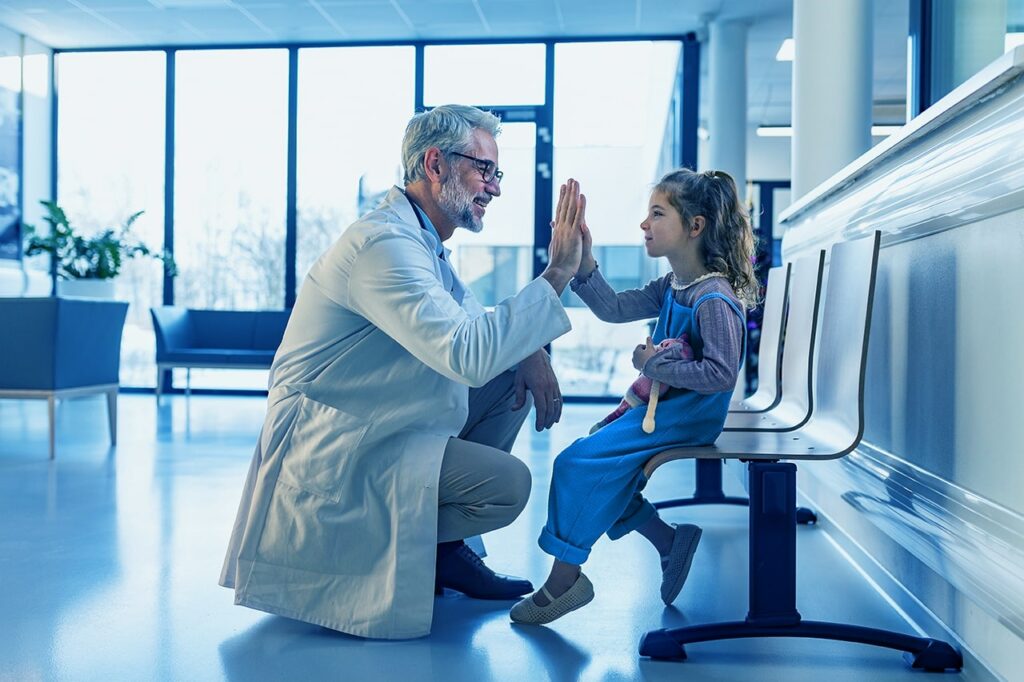 Doctor saludando a su paciente en la sala de espera de un hospital infantil, antes de irse del lugar