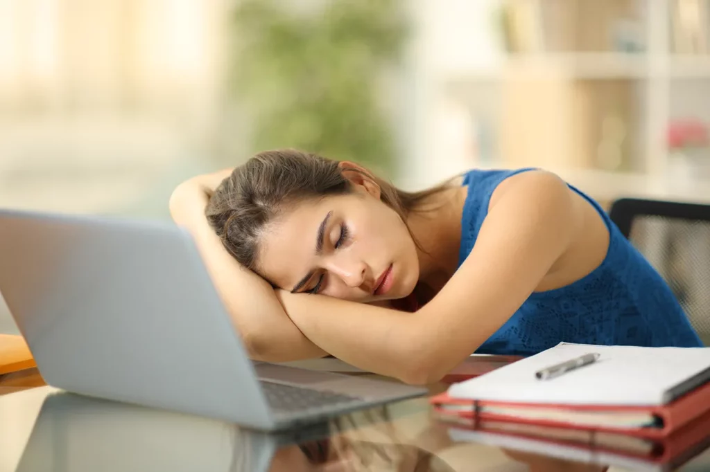 Mujer con narcolepsia, que es una condición que afecta el sueño, está dormida frente a su laptop de trabajo