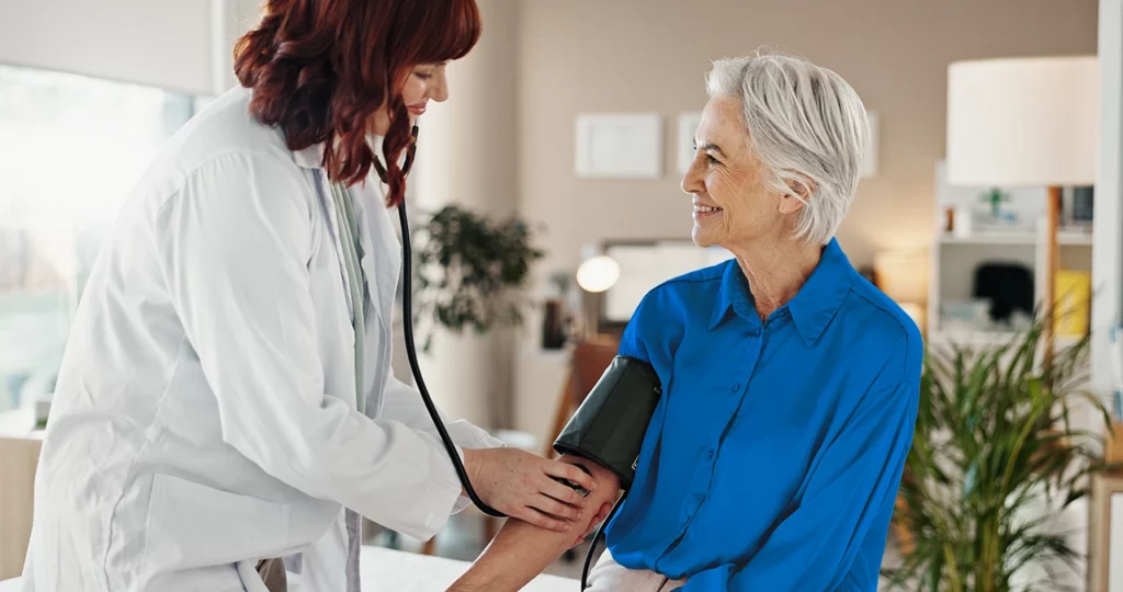 Especialista en cardiología revisando la presión arterial de su paciente durante una consulta.