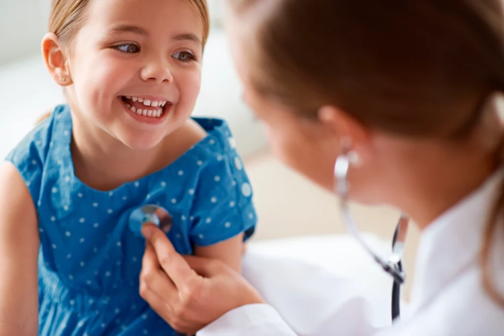 Médico revisando a su paciente posterior a la recuperación de una cirugía de tórax pediátrica.