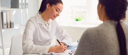 Médica escribiendo una receta médica para una paciente