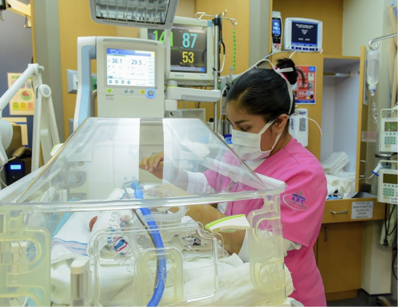 Médica revisando y asistiendo a un bebé dentro de una incubadora