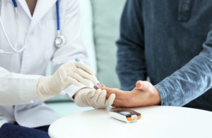 Médico realizando una medición del nivel de azúcar en sangre a un paciente