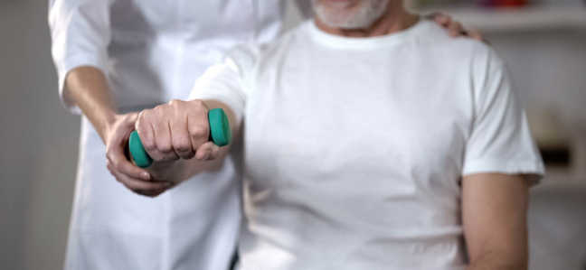 Paciente en rehabilitación sosteniendo una mancuerna. Paciente en rehabilitación sosteniendo una mancuerna.
