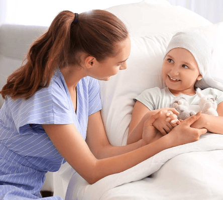 Enfermera tomando las manos de niña sonriente.
