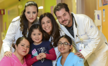 Médicos pediátras posando junto a niños sonrientes