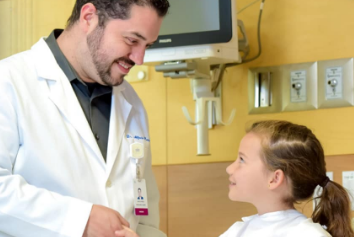 Médico sonriente estrechando manos con una niña que goza de salud
