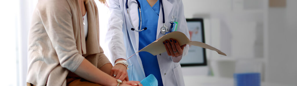 Médica leyendo un documento junto a una paciente