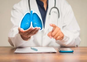 Doctor sostiene una imagen de los pulmones, explicando sobre el enfisema pulmonar que es y sus causas. Doctor sostiene una imagen de los pulmones, explicando sobre el enfisema pulmonar que es y sus causas.