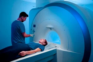 Mujer por empezar su resonancia magnética, siendo apoyada por un técnico que está ajustando el equipo