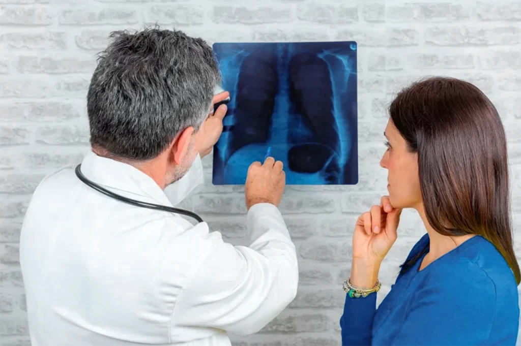 Cirujano cardiotorácico mostrando radiografía a una mujer, para explicarle la situación de su corazón y pulmones.