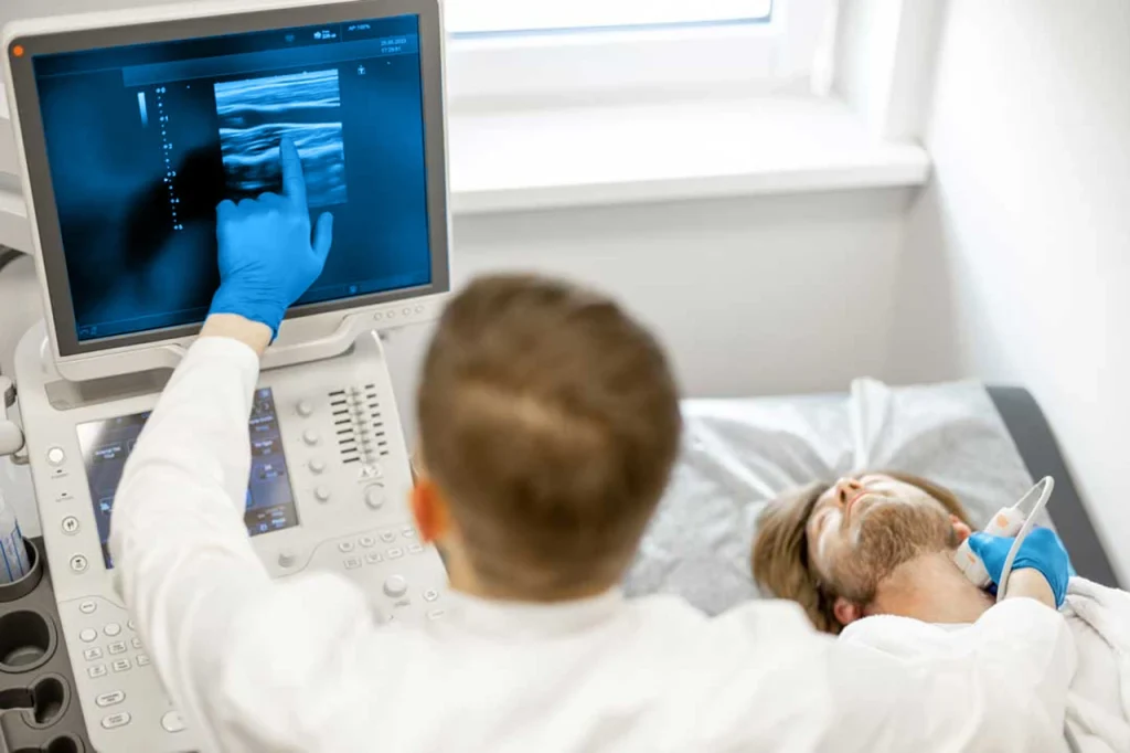 Joven acostado durante un procedimiento de ultrasonido Doppler, mientras el médico diagnostica algo en la arteria carótida.