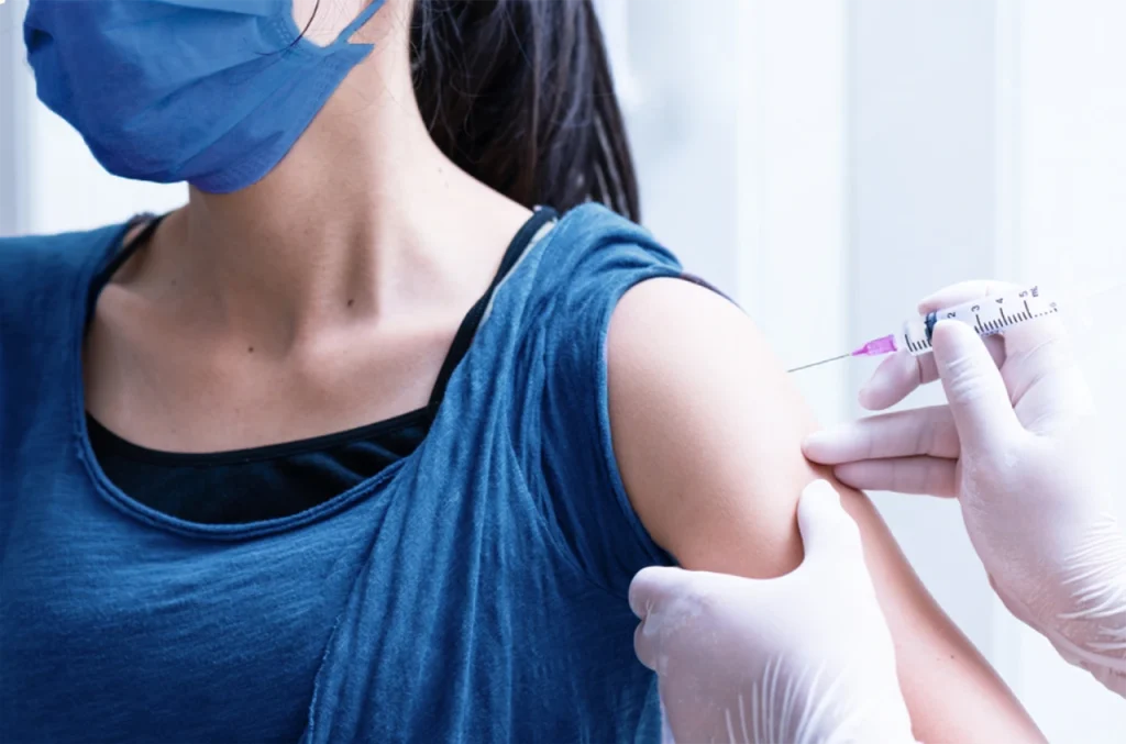 Especialista aplicando una vacuna de VPH en una mujer en su brazo, para prevenir complicaciones futuras de esta enfermedad.