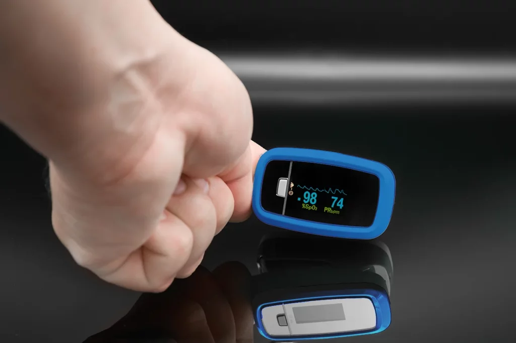 Hombre empleando un oxímetro para revisar si presenta una frecuencia cardíaca normal o está alterada.