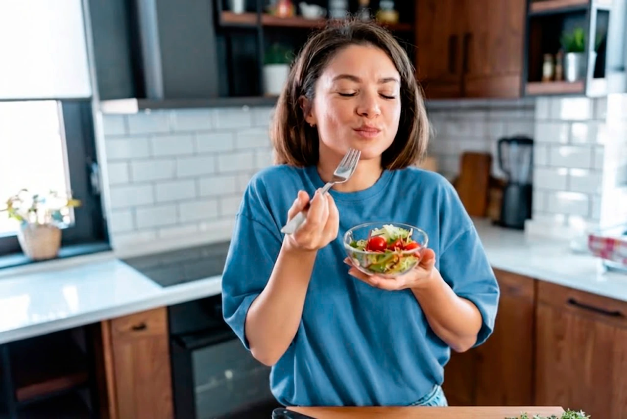 Mujer comiendo sano, como parte de su tratamiento más allá de los medicamentos para la gastritis.