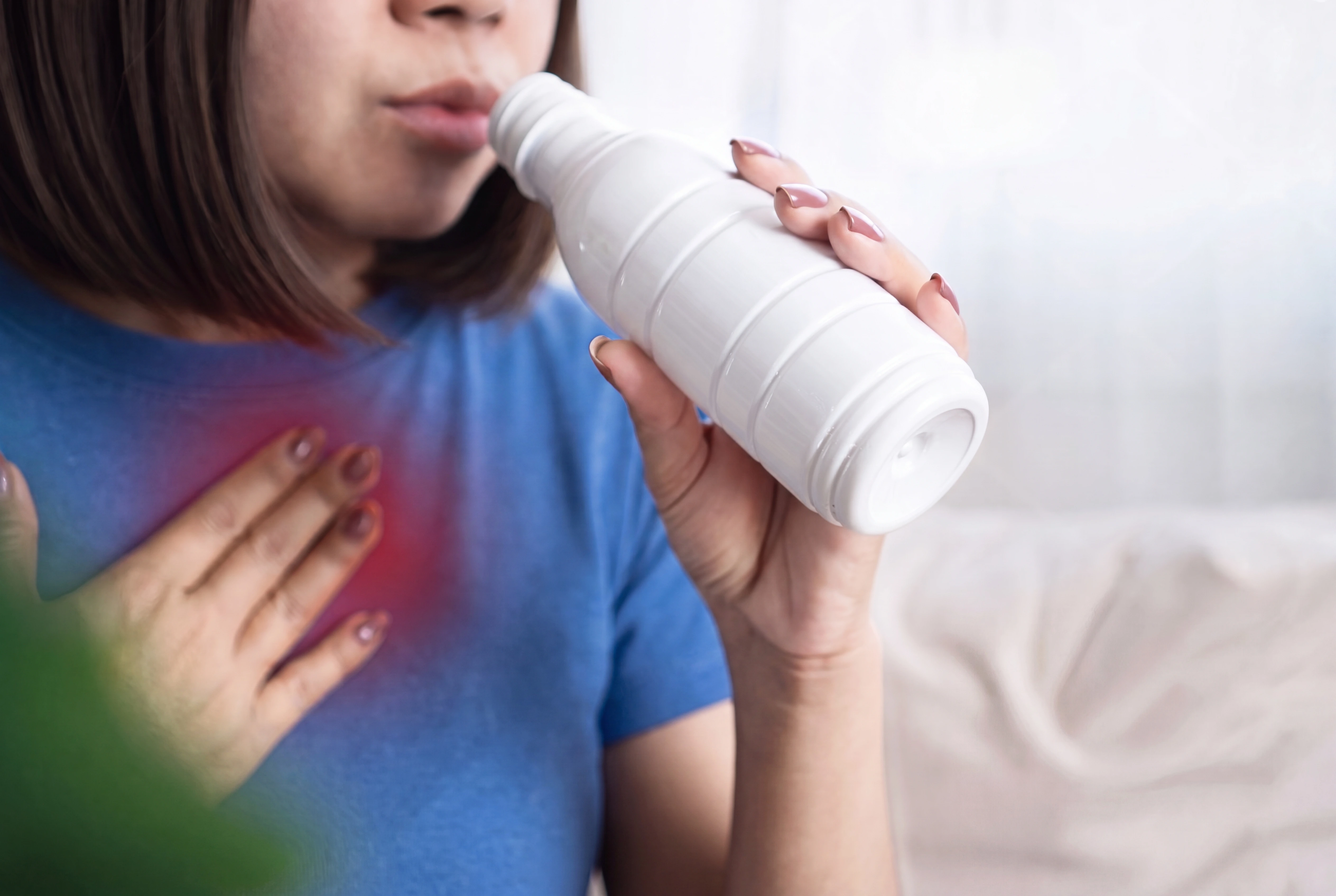 Mujer con agruras toma un líquido, de una botella, para aliviar los síntomas. Mujer con agruras toma un líquido, de una botella, para aliviar los síntomas.