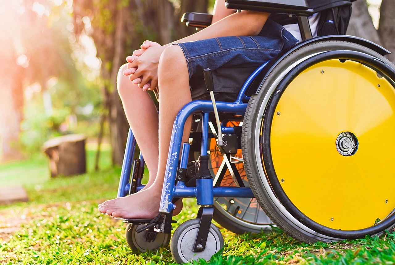 Paciente con ataxia sentado en una silla de ruedas, tomando el sol en el jardín.