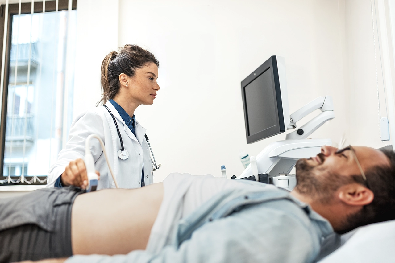 Especialista en gastroenterología realizando una ecografía abdominal a un paciente.