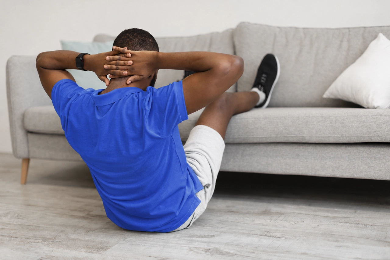 Hombre haciendo abdominales en casa como parte de su rutina de ejercicio para mejorar la salud del hombre.
